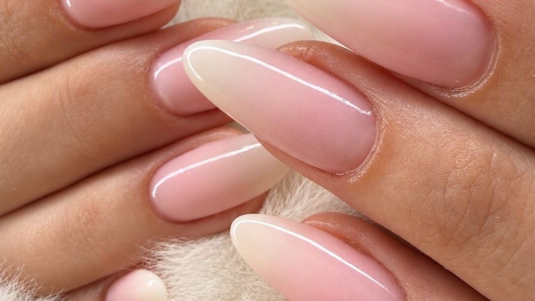Nude amandelnagels met een witte French op een witte vacht
